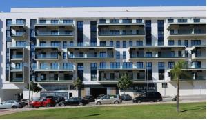 duży apartamentowiec z samochodami zaparkowanymi na parkingu w obiekcie Teatinos Suite w Maladze