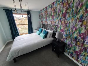 a bedroom with a bed with a colorful wall at EDEN Apartment, Oban in Oban