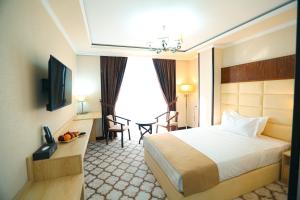 a hotel room with a bed and a table and chairs at Royal Grand Hotel, Turkistan in Türkistan +48 photos