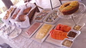 una mesa cubierta con bandejas de diferentes tipos de alimentos en Chalés Ancoradouro en Boracéia