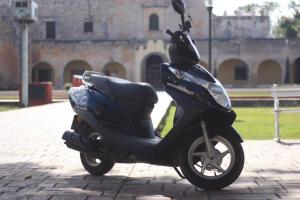 a black scooter parked on a brick sidewalk at Jalach Uinik, Hotel Real Maya 4 in Valladolid