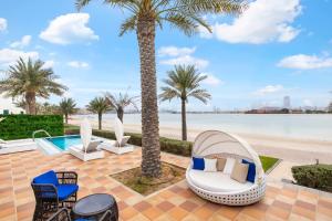 a patio with chairs and palm trees next to the beach at FAM Living - Sarai Beachfront Villas - 2 in Dubai