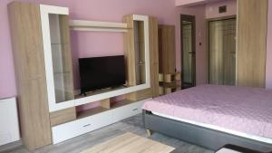 a bedroom with a bed and a flat screen tv at Къща за гости Роял in Sandanski