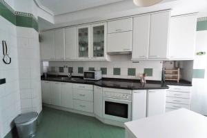cocina blanca con armarios blancos y microondas en Apartamento moderno muy acogedor y luminoso •León en León