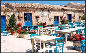 a restaurant with tables and chairs in front of a building at Mediterraneo Apartments ARGENTO in Marzamemi