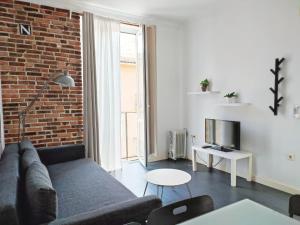 - un salon avec un canapé et un mur en briques dans l'établissement Flats Friends Torres Quart, à Valence