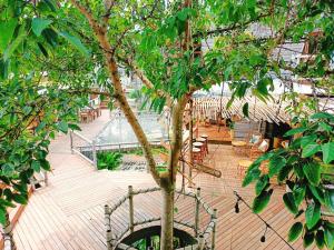 um deque de madeira com uma árvore, mesas e cadeiras em The Mud - Eco Hotel em Ban Bang Po