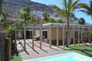 a house with a swimming pool and palm trees at Villas de Taurito in Taurito