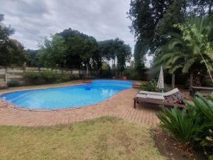 una piscina en un patio con un banco en SM Africa Guest House, en Alberton