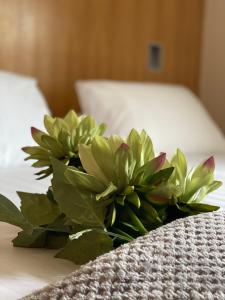 a bouquet of flowers in a white vase on a bed at Rooms at 1703 in Dunfermline
