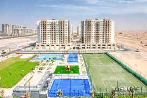 an apartment complex with a tennis court in front of a beach at Chic 1BR in Town Square UNA Dubailand by Deluxe Holiday Homes in Dubai