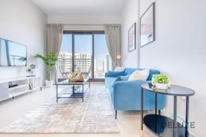 a living room with a blue couch and two tables at Chic 1BR in Town Square UNA Dubailand by Deluxe Holiday Homes in Dubai