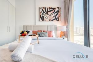a white bedroom with a large bed and a window at Chic 1BR in Town Square UNA Dubailand by Deluxe Holiday Homes in Dubai +26 photos