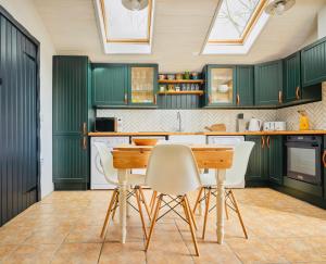 una cocina con armarios verdes y una mesa y sillas de madera. en Great Lilly Cottage, en Barnstaple