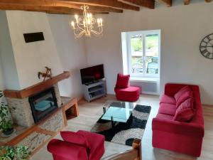 a living room with red furniture and a fireplace at la longere de Lor'Phée in Chantepie