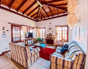 a living room with two couches and a tv at Pousada Quintal da Lua in Capitólio