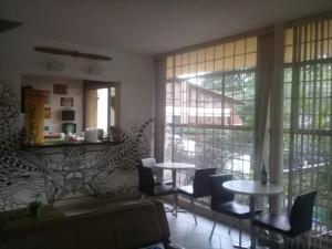 a living room with tables and chairs and windows at Hangar Rio Hostel in Rio de Janeiro