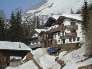 un edificio en una colina nevada con una montaña en Pension Sonnleitner, en Heiligenblut