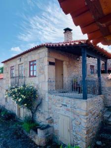 ein Steinhaus mit einer Veranda und einem Balkon in der Unterkunft Casas do Juizo - Country Houses in Juizo