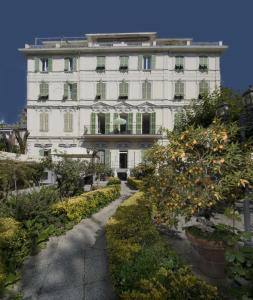 a white building with a garden in front of it at Hotel Alexander & Spa in Sanremo