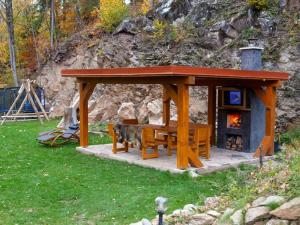 einem Holzpavillon mit einem Tisch und einem Kamin in der Unterkunft Luxury Chalet near Ski area in Benecko in Mrklov