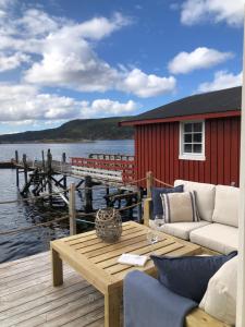 a wooden deck with a table and chairs on a dock at The Boathouse in Råkvåg