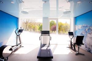 un gimnasio con dos máquinas de correr y una gran ventana en Schwitzer's Hotel am Park, en Waldbronn