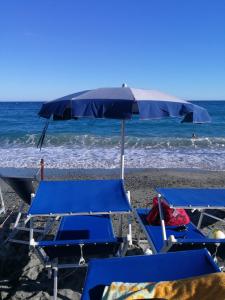 un grupo de sillas azules y una sombrilla en una playa en Celle mare con posto auto coperto, en Celle Ligure