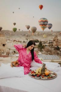 a woman sitting on a bed with a plate of food at Roma Cave Suite in Göreme