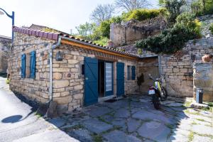 een klein stenen huis met een motor buiten geparkeerd bij Petit gite du Bistrot d ici in Saint-Saturnin