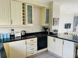 a kitchen with white cabinets and black counter tops at Unit 4 Umzimkulu - Mangroves beach estate in Melville