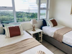 twee bedden in een kamer met twee ramen bij Unit 4 Umzimkulu - Mangroves beach estate in Melville