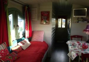 a small room with a red couch and a table at Gîtes Les Perouilles - La Roulotte Climatisée avec Jacuzzi et Piscine Hors sol de Josépha in Puymiclan