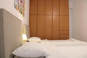 a bedroom with two beds and wooden cabinets at Kalamaki Plaza Apartments in Kalamaki
