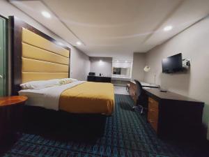 a hotel room with a bed and a desk and a television at Scottish Inns & Suites in Springdale
