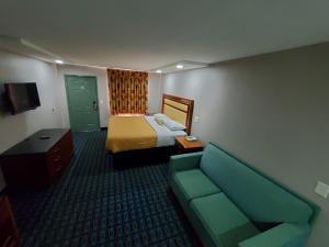 a hotel room with a bed and a couch at Scottish Inns & Suites in Springdale