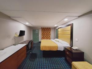 a hotel room with a bed and a desk and a sink at Scottish Inns & Suites in Springdale