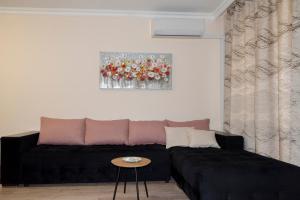 ein Wohnzimmer mit einem schwarzen Sofa und einem Tisch in der Unterkunft Apartment EliMar in Burgas City