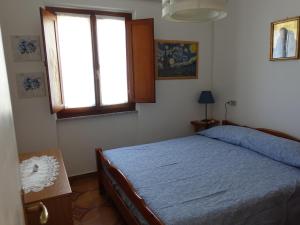a bedroom with a blue bed and a window at Turchese in Pomonte