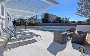 a patio with lounge chairs and a swimming pool at Apartment PASMAN - appartement 50 m2 et piscine in Pakoštane