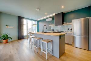 a kitchen with a refrigerator and a counter with stools at Les Lofts Dorchester - Par Les Lofts Vieux-Québec in Quebec City