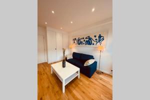 - un salon avec un canapé bleu et une table dans l'établissement Deauville Plage - Balcon, Vue Mer & Ville à pied, à Deauville