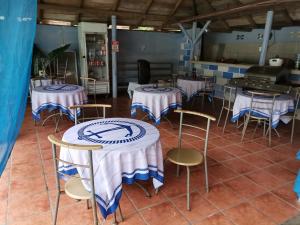 eine Gruppe von Tischen und Stühlen mit blauen und weißen Tischdecken in der Unterkunft Hostel Antorchas in Dominical