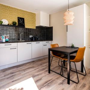 a kitchen with white cabinets and a black table and chairs at Charley's Home 2 personen in Westkapelle