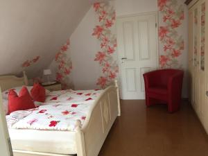 - une chambre avec un lit et une chaise rouge dans l'établissement Fewo Elbblick im Haus Lühegarten, à Grünendeich