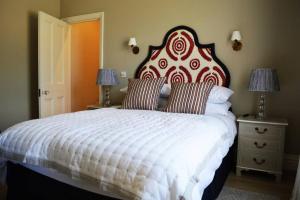 a bedroom with a large bed with a red and white headboard at Cockloft Romantic Countryside Hideaway in Bishops Cannings