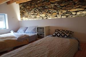 a bedroom with a bed and a stone wall at Casa do Avô Alváro - Refugio do Rei in Casal do Rei