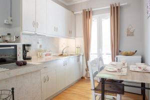 a kitchen with white cabinets and a table and a dining room at Akratos wine house in Nydri