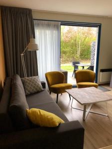 een woonkamer met een bank, stoelen en een tafel bij Appartement De Wadloper, Resort Amelander Kaap! in Hollum