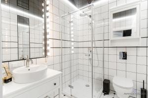 biała łazienka z umywalką i prysznicem w obiekcie Apartament Black w mieście Mielno